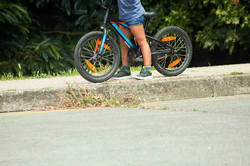 kid cycling on sidewalk
